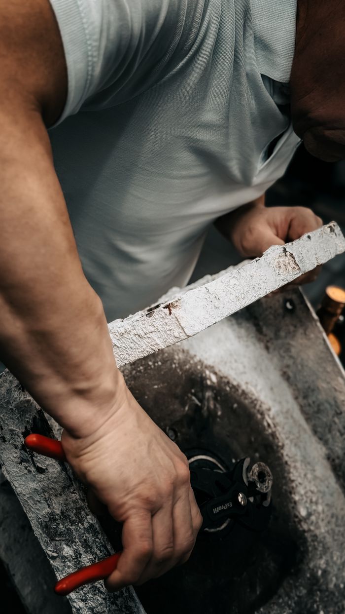 Craftsman skillfully repairing machinery with tools. Focus on hands and equipment.